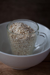 Oat flakes in a glass mug on a wooden background selective focus