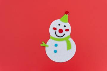 flat smiling toy christmas snowman with green scarf on red