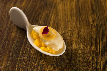 Baru ice cream with chopped mango and cornmeal in a spoon. Taste gastronomy finger food