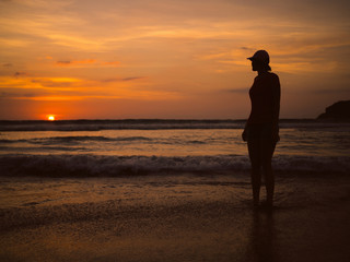 Young beautiful woman in a baseball cap at sunset looking at the horizon. Sea sunset landscape