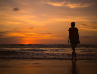 Young beautiful slim girl on the beach watching the sunset and the horizon. Sea sunset landscape