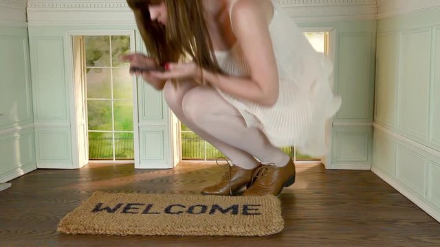 Young woman in small house with key and welcome mat