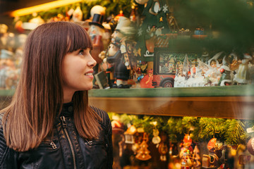 beautiful woman holding christmas present in front of christmas toys shop