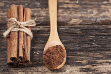 Cinnamon pile and powder in wooden spoon on the wooden table