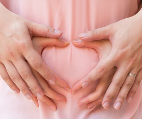 young couple putting hands on belly shaped like a heart