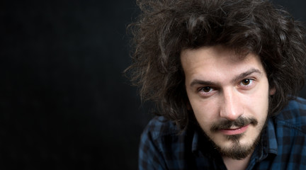 Portrait of a fashionable young man with funny hair on dark back