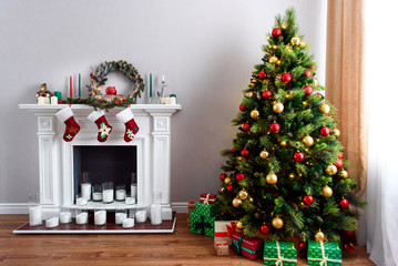 A cozy traditional Christmas house decorations, green tree full of toys and a beautiful fireplace with red socks for presents hanging on it