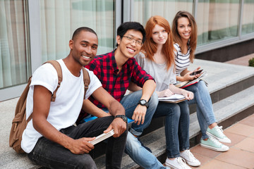 Cheerful young people sitting outdoors together
