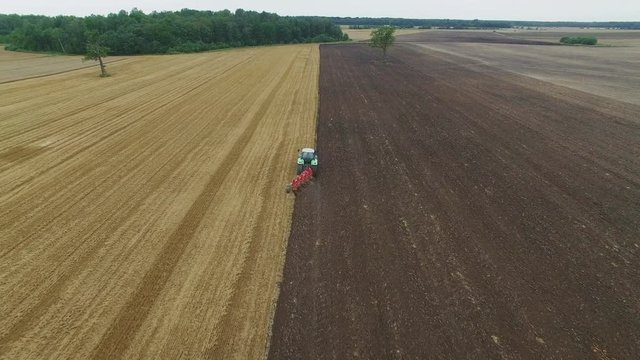 Aerial Shot of a Tractor Plowing Field. Clear Line of Completed Work is Visible.