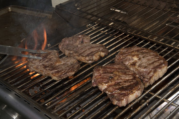 Four steaks cooking on the grill of a barbecue - USA - 2016