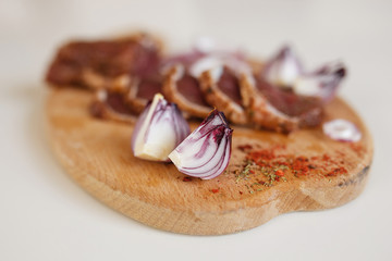 Salted meat with spices on a wooden board
