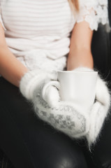 hands in white mittens and mug of tea or coffe
