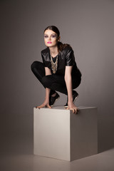 Sexual dark- haired model sitting on top of grey cube photo