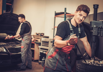 Professional car  mechanic replace tire on wheel in auto repair 