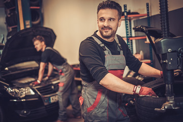 Fototapeta na wymiar Professional car mechanic replace tire on wheel in auto repair 
