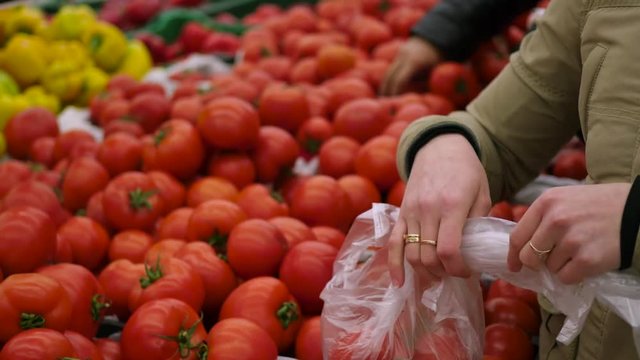 Woman Chooses Vegetables Tomatos In Supermarket