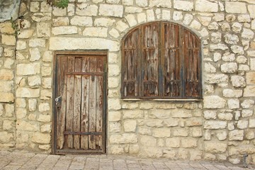 Ancient wooden door and window in old stones brick and cement wall