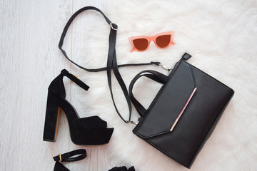 Fashion concept. Black handbag, shoes and pink glasses on a white background. top view