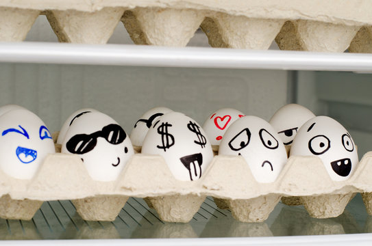Eggs with painted emotions in a tray on a shelf in the refrigerator