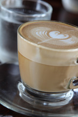 Heart shape froth on top of hot cappuccino coffee in clear glass.
