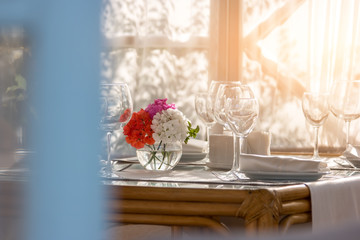 Flowers on the dining table. Plate and empty wineglasses. Invite your relatives for breakfast. Perfect order and cleanliness.