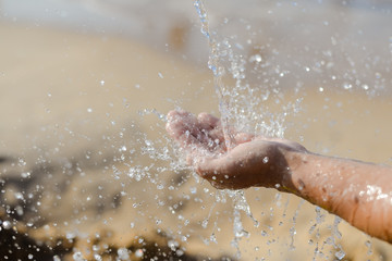 Fototapeta premium Closeup on human hand catching water, sunny summer outdoors background