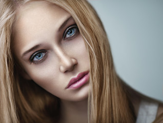Naklejka premium Closeup beauty portrait of young beautiful blonde woman with long hair and beautiful makeup. Smoky eyes.