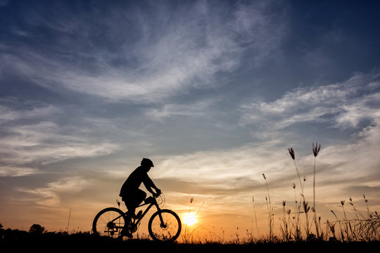 silhouette of bicycle rider at sunset - Powered by Adobe