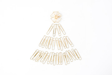 creative arrangement of bright golden christmas tree made of clips on white background. flat lay, top view
