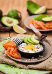 Fototapeta na wymiar Fried egg, avocado and smoked salmon in frying pan