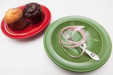delicious donut and muffin, fork and tape-measure on plate, on white backgrounds, diet concept