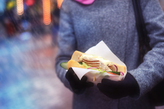 Sandwich in the woman`s hands. Street food.