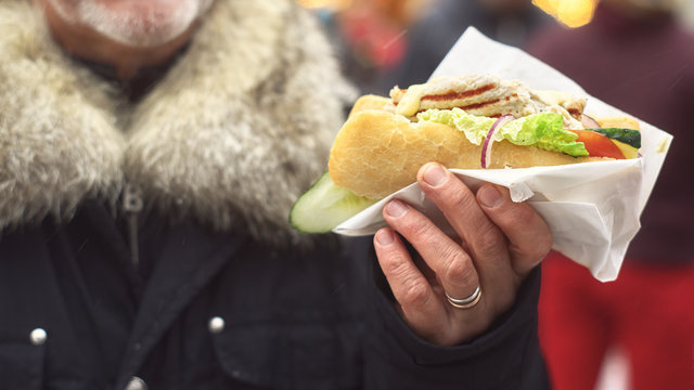 Sandwich in the man`s hands. Street food.