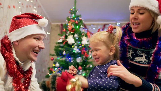 Little happy girl holding jingle bells in hand. Christmas concept. Parents joying 