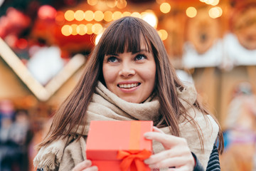 beautiful woman holding a present box on a christmas market