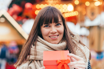 beautiful woman holding a present box on a christmas market