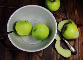 зеленые яблоки в металлической миске на деревянном столе