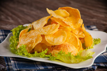 homemade potato chips on a white plate, on a linen towel around