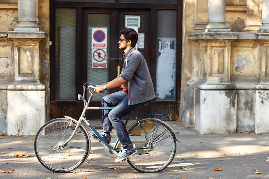 Young handsome ride a bicycle on sidewalk in the city.