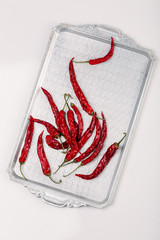 red dry chili pepper on on a metal vintage tray isolated on white background 