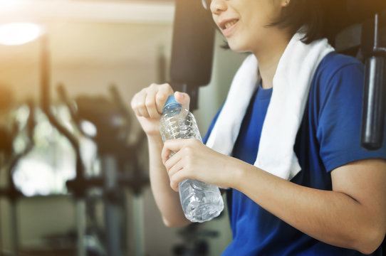 Asian woman holding bottle of water after  workout.