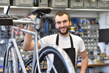 freundlicher Zweiradmechnaiker in einer Fahrradwerkstatt repariert Räder