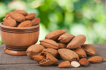 almonds in a bowl on the old wooden board with blurred garden background