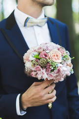 Groom hand holding bouquet fresh flowers close up with roses and