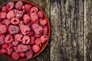 Frozen raspberries on wooden background. Top view. Space for text.