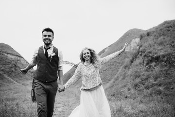 Handsome groom and beauty bride run in the nature