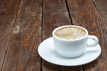 White coffee cup with foam on dark wood table
