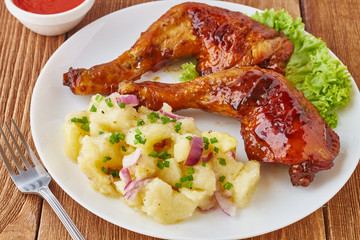 Grilled chicken legs with potato salad, vegetables and tomato sauce