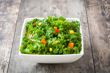Kale salad in bowl with carrot, pepper and sweet corn on wooden background   © chandlervid85