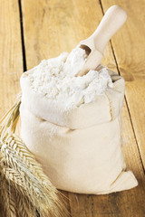 Flour in bag and wheat ears on a wooden background. Top view, co
